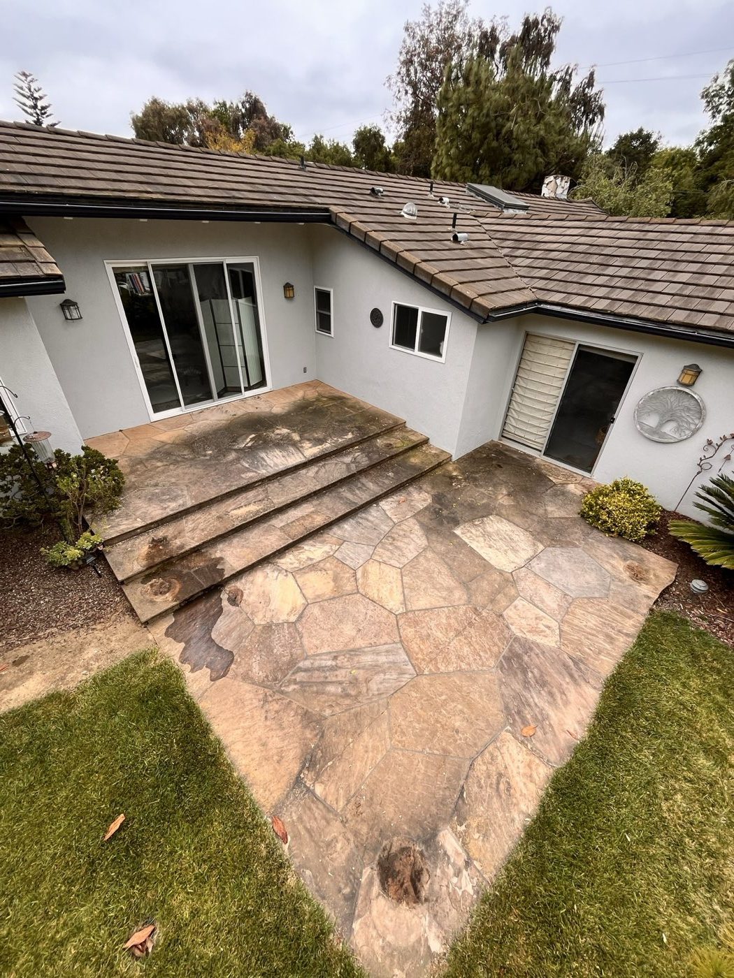 Flagstone courtyard patio greyed and blotchy with organic growth before pressure washing in Fresno