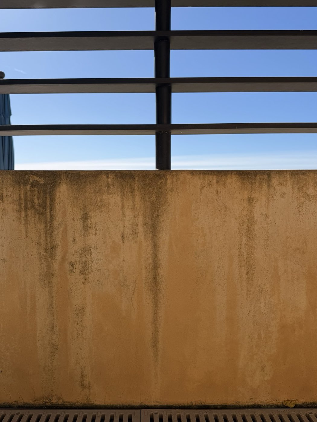 Stucco privacy wall streaked with brown irrigation and dirt staining before soft washing