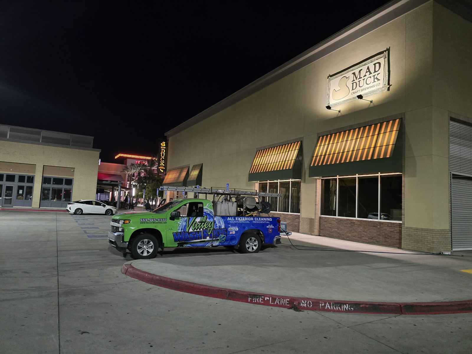 Valley Wash Pros truck working a shopping center storefront and parking lot at night