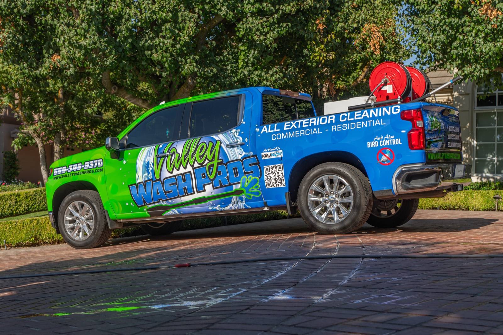 Clean green-and-blue wrapped Valley Wash Pros fleet truck with hose reels