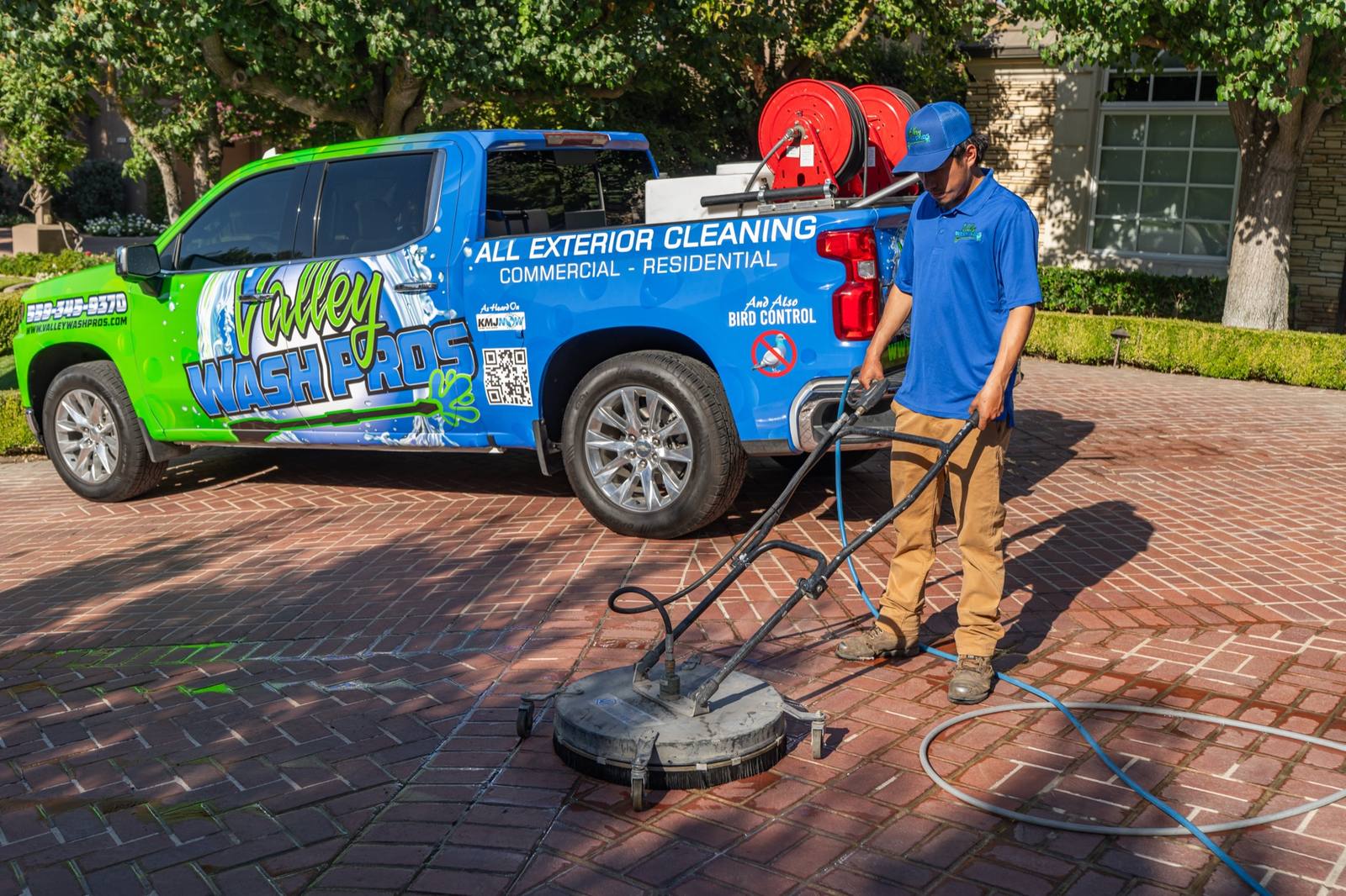 Valley Wash Pros tech running a surface cleaner on a brick-paver driveway in Fresno